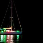 Sailboat at night with navigation lights glowing brightly.
