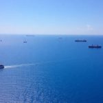 Various boats and ships on vast blue ocean.
