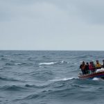 Small boat on rough water, cloudy sky.