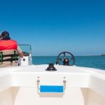 A boat on calm water with a person at the helm.