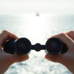 Boater with stabilized binoculars on a rocking boat.