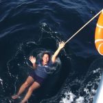 Person in water near boat, life ring.