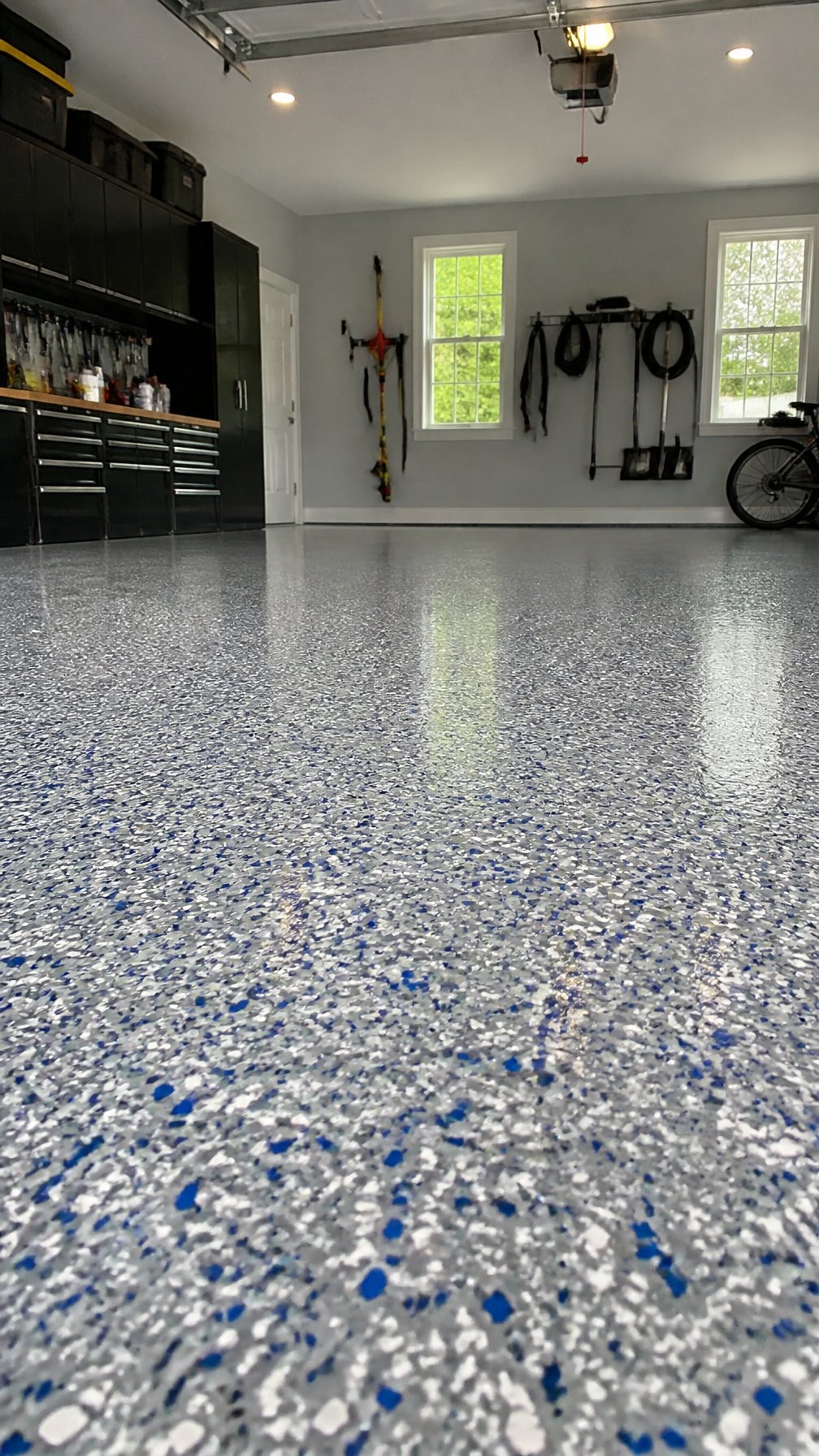 A clean and organized garage with a glossy, speckled epoxy floor featuring colorful vinyl flakes.